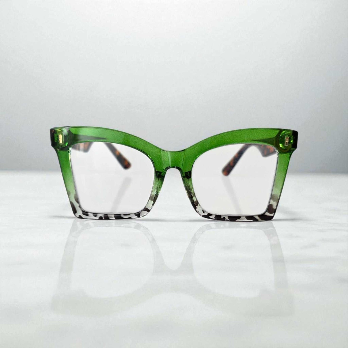 green and bold reading glasses with blue light filter and green-to-tortoise gradient frame on white surface