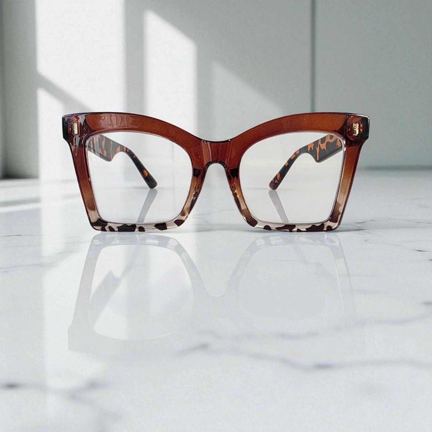 Animal print and tortoiseshell large square reading glasses with blue light filter lenses on marble surface