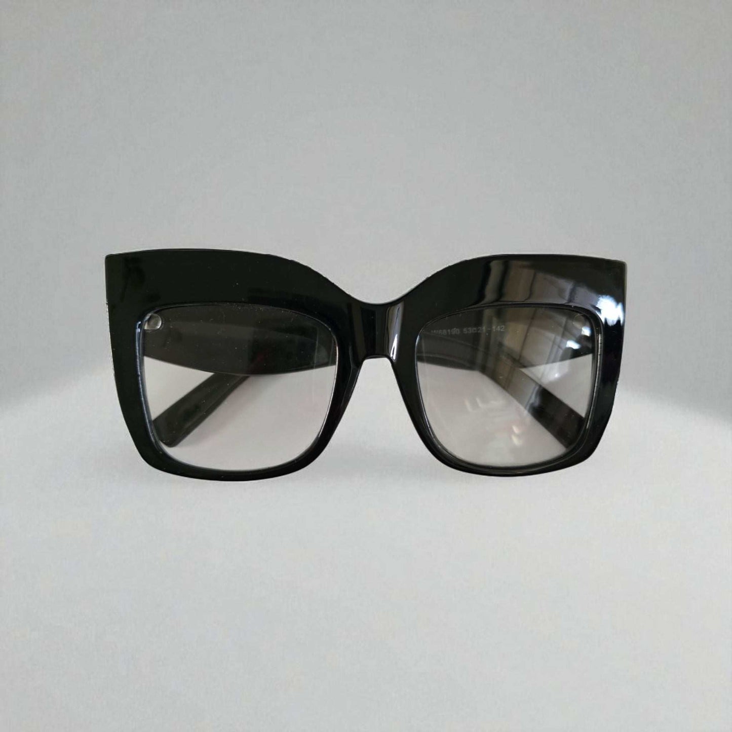 Black oversized cat eye reading glasses with thick glossy acetate frames and clear blue light filtering lenses.