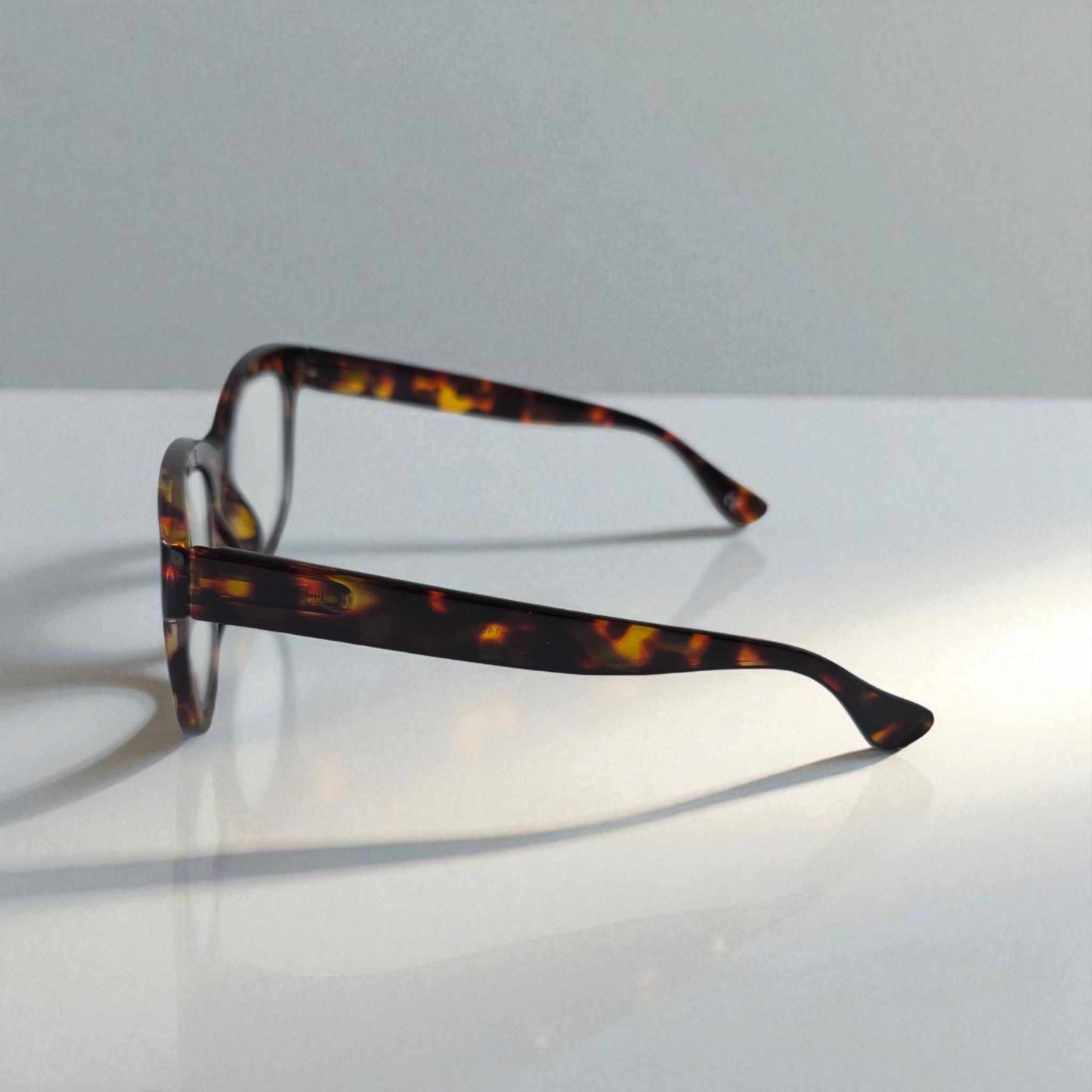 Bold tortoiseshell cat eye reading glasses with blue light filter and black frames on white surface