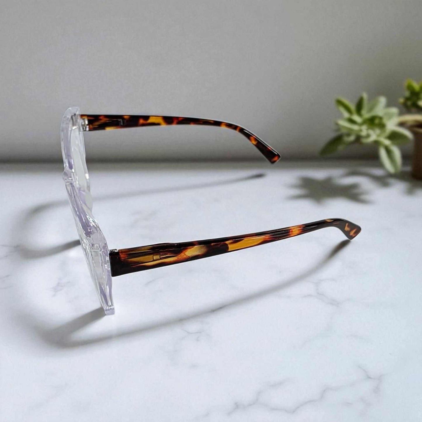 Side view of icy crystal clear tortoiseshell reading glasses with blue light filter on marble surface