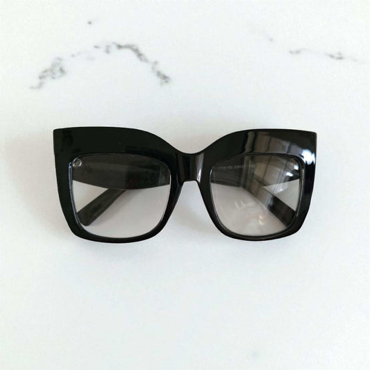 Black oversized cat eye reading glasses with thick glossy frames and slightly tinted lenses.
