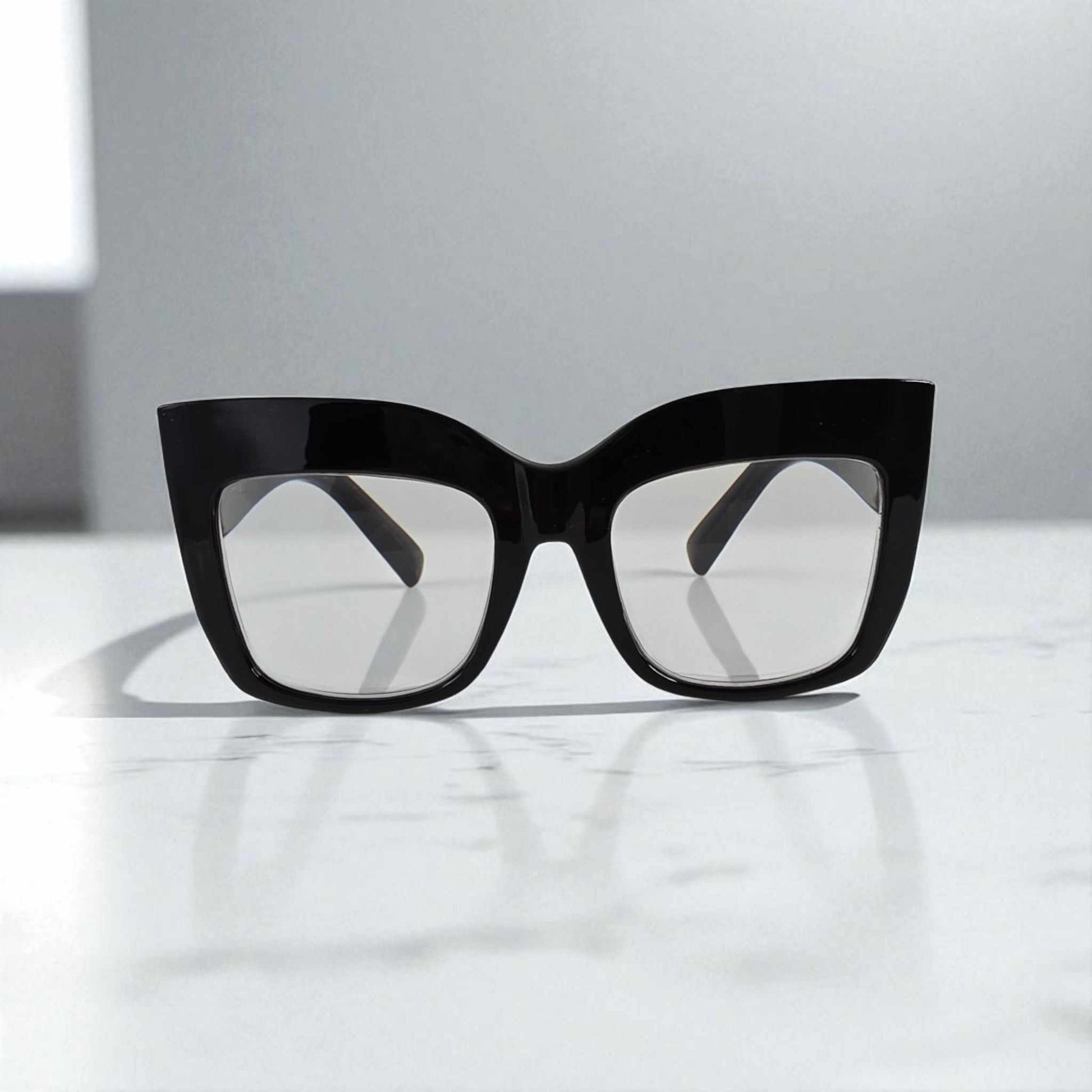 Black oversized cat eye reading glasses with blue light filter lenses on white surface